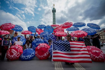 Personas con paraguas y la leyenda "Salvemos la democracia" participan en la protesta "Sin reyes" en París.