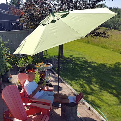 Un hombre tumbado en una hamaca bajo la sombrilla.