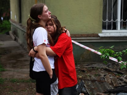 Dos personas esperan noticias sobre desaparecidos que permanecen debajo de los escombros junto a un edificio bombardeado por Rusia en Kiev este jueves.