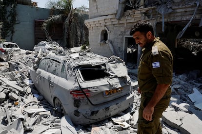 Un soldado israelí camina junto a un vehículo destruido tras el impacto de misiles lanzados desde Irán contra un edificio residencial en Tamra, en el norte de Israel, este domingo.