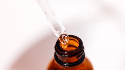 Un técnico de laboratorio introduce gotas de un producto químico en un frasco.