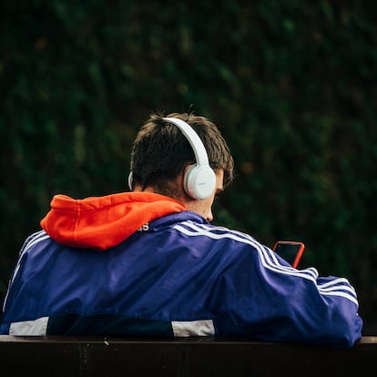 Un chico joven utiliza su teléfono móvil en un parque. 