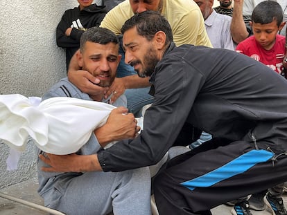 Dos hombres abrazan el cadáver de una víctima de los bombardeos israelíes en Gaza, el pasado lunes.