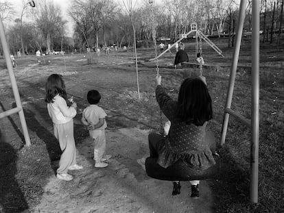 Varios niños juegan en unos columpios de un parque en la Casa de Campo de Madrid.